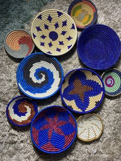 several bowls are arranged on the floor in different colors and sizes, with one bowl holding an abstract design