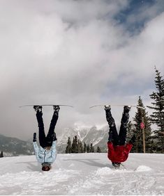 two snowboarders are upside down in the snow