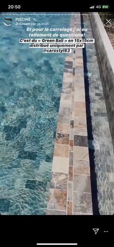 an image of a swimming pool with water running down the side and tile on the edge