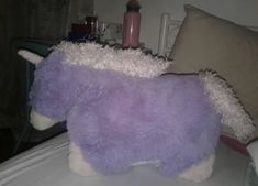 a purple stuffed animal sitting on top of a bed