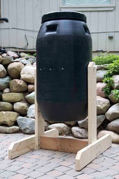 a large black tank sitting on top of a wooden stand in front of some rocks