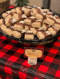 a table topped with a pie covered in marshmallows on top of a red and black checkered table cloth