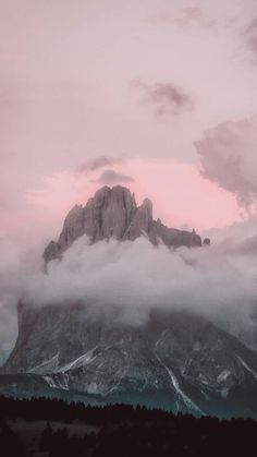 the mountains are covered in clouds and pink hues