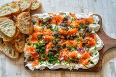 a wooden cutting board topped with bread slices and an appetizer on top of it