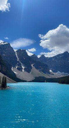 the sun shines brightly on some mountains and blue water