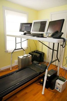 three computers are sitting on top of a treadmill in the corner of a room