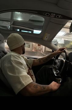 a man sitting in the driver's seat of a car with his hand on the steering wheel