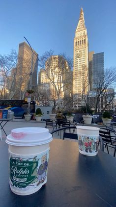 two ice cream cups sitting on top of a table in front of a city skyline