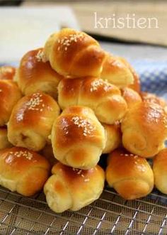 a pile of bread rolls sitting on top of a cooling rack covered in sesame seeds