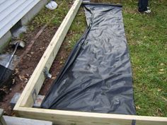 a man standing next to a black tarp in the grass