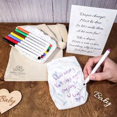 a person writing on a piece of paper next to some crayons