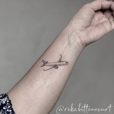 a small airplane tattoo on the left wrist and right hand is shown in black ink