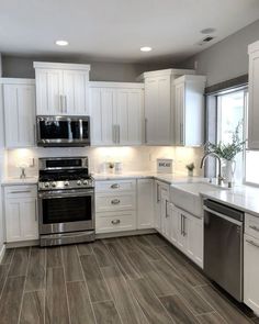 a large kitchen with white cabinets and stainless steel stove top oven, dishwasher and microwave