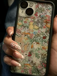 a woman holding an iphone case with flowers and animals on it