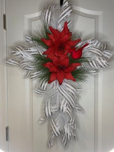 a cross decorated with poinsettis and feathers on a door