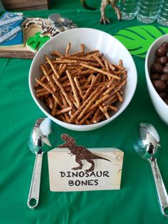 two bowls filled with chocolate covered pretzels next to spoons on a green table cloth