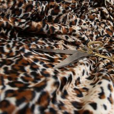 a pair of scissors cutting through the animal print fabric on a bed sheet or blanket