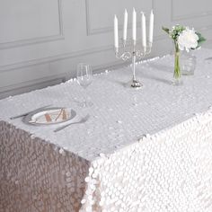 a table topped with a white table cloth covered in lots of bubbles next to a vase filled with flowers