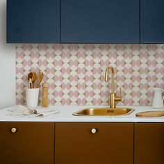 a kitchen counter with a sink and wooden utensils on it next to blue cabinets