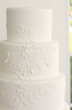 a three tiered white wedding cake on a table