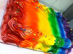 a rainbow cake with icing and sprinkles on it