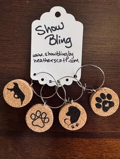 four wine charms with dog paw prints on them and a tag that says show bling