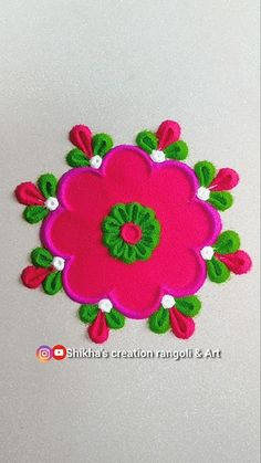 a pink flower with green leaves and white flowers on the center is surrounded by red, green and white felt