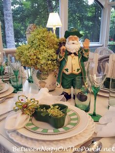 a table set with plates, glasses and vases for st patrick's day