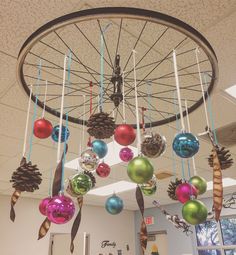 christmas ornaments hanging from the ceiling in an office space with a bicycle wheel and pine cones