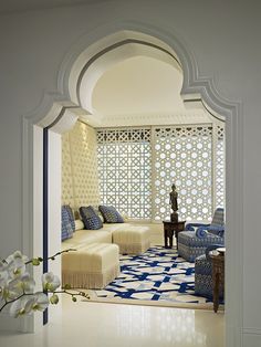 a living room with blue and white furniture in the center, along with an archway leading to another room