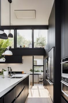 Modern kitchen with black cabinetry, stainless steel appliances, and large windows allowing natural light. Fold Down Table