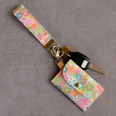 a key fobring is sitting on top of a flowered fabric case with keys in it