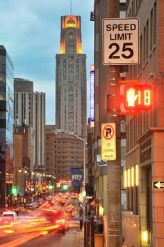 a city street filled with lots of traffic next to tall buildings and lights at night