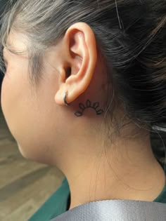 a woman's ear has a small flower tattoo on it