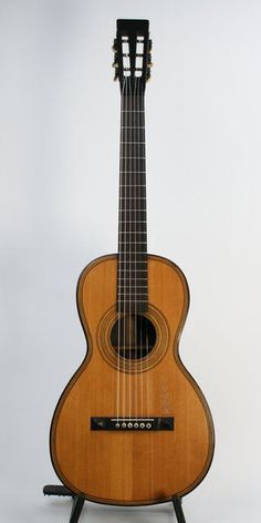 an acoustic guitar sitting on top of a stand in front of a white background,