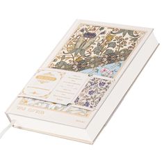 an open white book with floral designs on it's front and back pages,