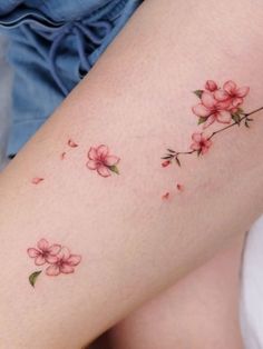 a close up of a person's legs with tattoos on them and pink flowers