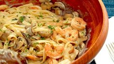 a wooden bowl filled with pasta and shrimp