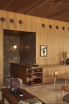 a living room filled with lots of furniture and wooden paneling on the walls,