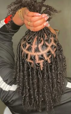 a woman with long, curly hair sitting on a chair holding her hand up to her head