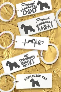 four keychains with dogs on them are shown in black and white, against a gold foil background