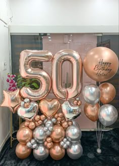 balloons and flowers are arranged in the shape of an 50th birthday sign with gold, silver and pink balloons