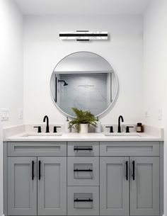 a bathroom with two sinks and a large round mirror