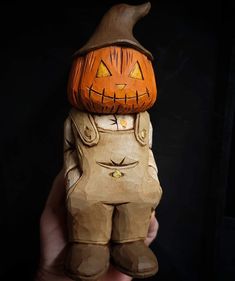 a person holding up a wooden carved pumpkin