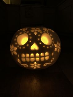 a lit up pumpkin sitting on top of a wooden floor