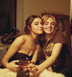 two young women sitting on the floor hugging each other