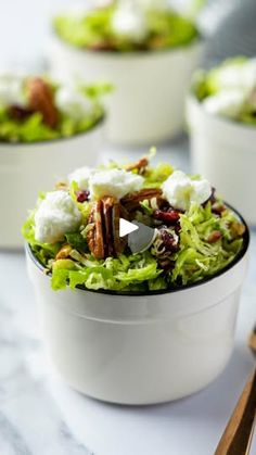 a white bowl filled with lettuce and pecans on top of a table