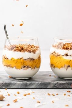 two desserts in glass bowls with spoons on a cutting board next to each other