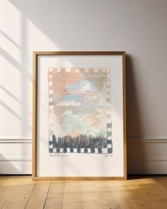 an art print on the wall in front of a wooden floor with a white frame