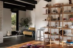 a living room filled with furniture and a fire place next to a brick wall in front of a window